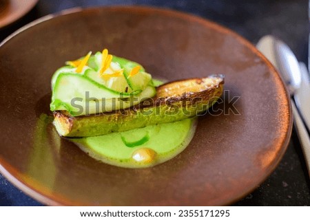 Exquisite vegetarian zucchini dish of modern French haute cuisine prepared with fresh organic ingredients from restaurant own garden and farm and beautifully served with sauce