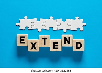 To Extend A Business Contract Or Time Extension Concept. The Word Extend On Wooden Cubes With A Connected Line Of Jigsaw Puzzle.