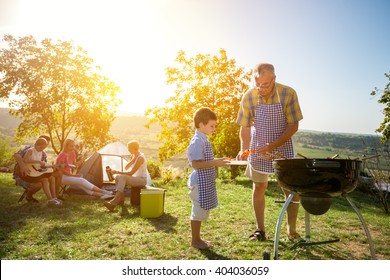 Extended family cooking barbecue in park