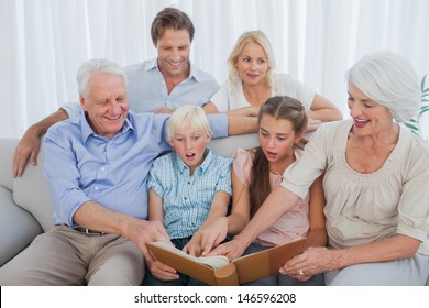 Extended Family Looking At Their Album Photo In The Living Room