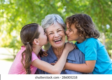 Extended family smiling and kissing in a park on a sunny day - Powered by Shutterstock