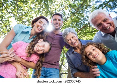 Extended family smiling in the park on a sunny day - Powered by Shutterstock