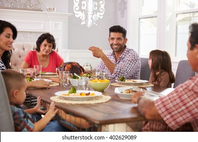 Extended Hispanic Family Enjoying Meal At Table