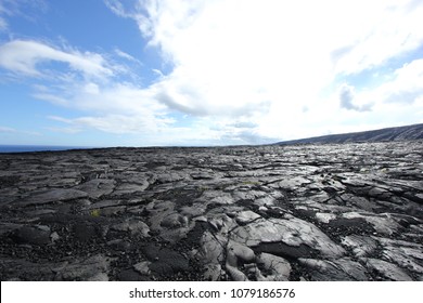 Extensive black barren volcanic rock surface with blue sky and clouds, Chain of Craters Road, Hawaii.