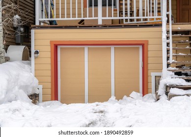 Exterior Of An Attached Single Car Garage Of Home With Snowy Driveway In Winter