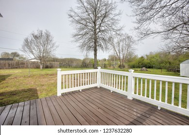Exterior backyard deck with white handrail and green grass. - Shutterstock ID 1237632280