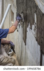 Exterior Basement Wall Waterproofing, Worker Installing  Waterproofing Tar Sealer. Selective Focus And Motion Blur.