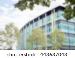 Exterior building architectural background of glass office buildign with sky and clouds in background and green trees in front