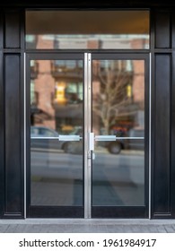 Exterior Building Entrance With Black Steel Double Glass Door And Defocused Reflection From Traffic And Neighboring Building. Commercial, Business Or Residential Lobby Entrance. Selective Focus.