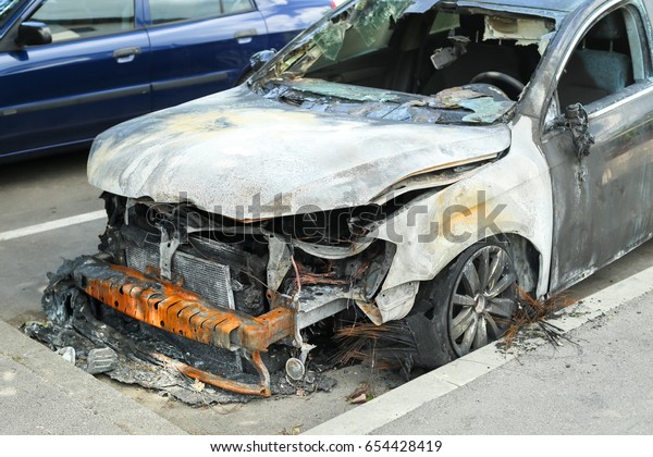 The\
exterior of a burned out car in a parking\
lot.