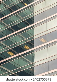 Exterior detail of downtown office building with ceiling light fixtures visible through reflective windows on an autumn afternoon