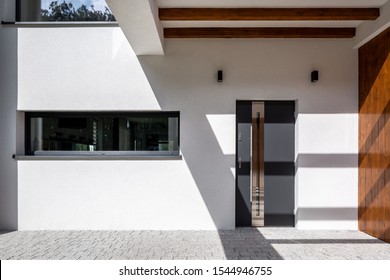 Exterior of elegant house with white facade, stylish doors, long window and wooden decorations