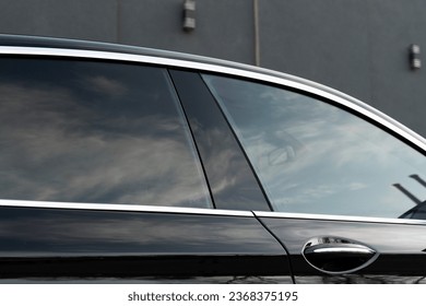 Exterior of executive luxury car of black color with tinted windows standing at parking outdoors. Modern design of expensive automobile