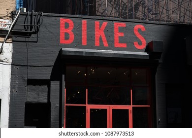 Exterior Of A Generic Bike Shop In New York. Bikes Painted In Red On Black Brick Building. Generic Bicycle Storefront Painted Red And Black. Facade Of A Bike Store In An Urban Area, USA.