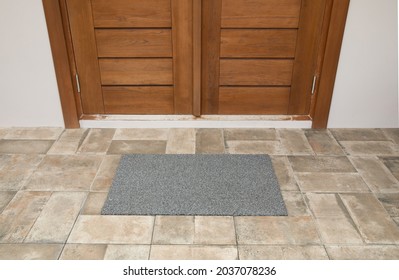 Exterior of a house with wooden door and gray tiled floor. 