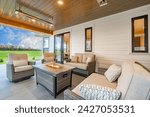 Exterior of a large modern farmhouse home white siding large front veranda porch with chairs and table wicker furniture bbq smoker electric heater gas fire place sunny and landscaped yard