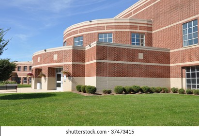 Exterior Of A Modern Brick High School By A Lush Green Lawn