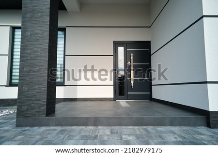 Exterior of modern contemporary comfortable house with front porch, stylish door, paved yard and shuttered windows
