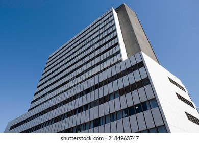 Exterior Of A Modern Office Building Made Of Glass And Plastic And Concrete Panels In Several Layers Against A Blue Cloudless Sky. Modern Rectangular Building With Many Windows. Real Estate