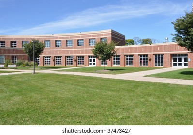 exterior of modern red brick school by a lush green lawn
