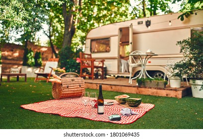 Exterior Of Motor Home With Picnic Stuff On The Foreground. Camping Trailer. Traveling Concept.