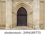 Exterior to an old christian church with wooden doors and stone brick walls