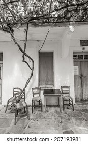 The Exterior Of An Old Coffee Shop, Located In A Small Village Of Ikaria Island, Greece, With Some Chairs And Tables Left Outside, Under A Pergola.