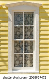 Exterior Of Old White Painted Window On Bright Yellow Clapboard House