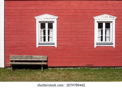 An exterior of an old wooden house on a summer day. The wooden bench is perfectly situated in the warm sunny spot.