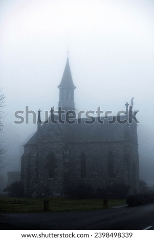 Exterior photo view of a small christian catholic chapel church building in the misty mist fog of Normandy seen with a backlight effect making it mysterious and legenday