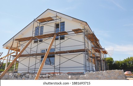 Exterior renovation of the house by rendering, insulating, plastering, applying stucco and painting the facade of the house on scaffolding.