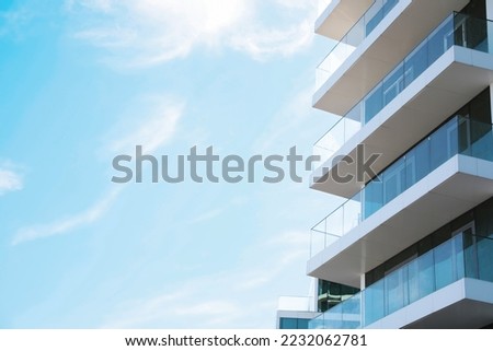 Exterior of residential building with balconies against blue sky, low angle view. Space for text