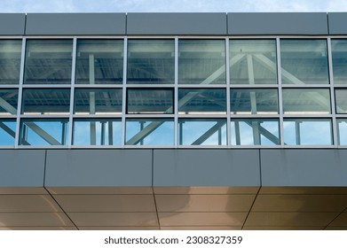 The exterior skyway of a contemporary commercial style building with aluminum metal composite panels and glass windows. The futuristic building has engineered diagonal cladding steel frame panels. - Powered by Shutterstock