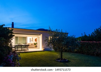 Exterior Of A Small Modern House With Garden. Night Situation