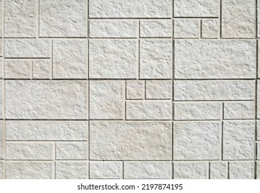 Exterior stone wall cladding made by white rock panels in tile shape of differen sizes. Background and texture.