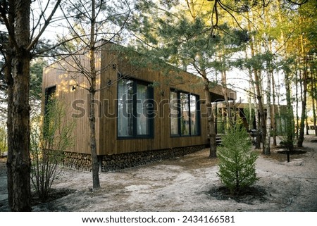 Exterior tiny wooden house with big windows for holidays hidden in the pine forest