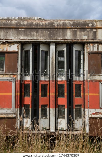 An exterior view of the back exit\
doors of an old weathered street car in field of\
grass\
