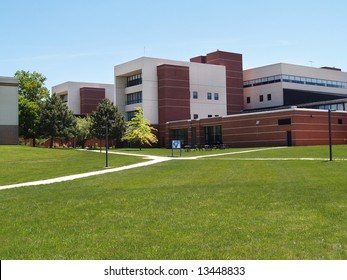 An Exterior View Of A College Building With A Large Grass Area In Front Of It