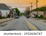 Exterior view down generic main street in small town USA as sunrise comes over illuminating sky beautiful orange colors in background