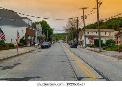 Exterior view down generic main street in small town USA as sunrise comes over illuminating sky beautiful orange colors in background