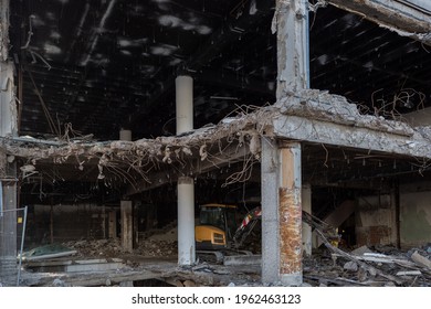 Exterior View Of Inner Part Of Remaining Office Building Demolition With Small Excavator Park Inside. Demolished Construction Site In The City.