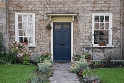 Exterior View And Leafy Green Garden Of A Beautiful Old Stone Cottage House On A Street In An English Town
