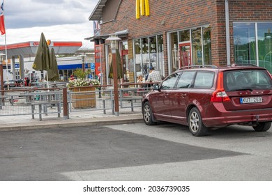 Exterior View Of McDonald's Near OKQ8 Gasoline Station. Family Has Dinner At Table. Sweden. Uppsala. 09.05.2021.