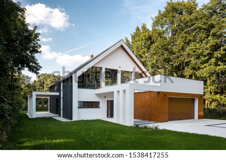 Exterior view of modern, white house with garage decorated with wood