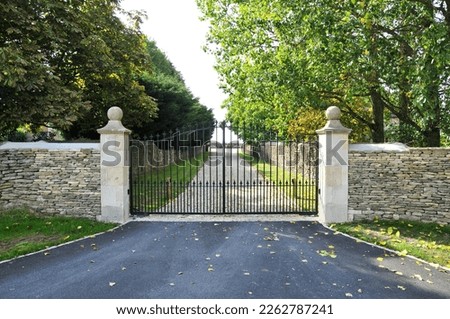 Exterior view of an old stone wall, ornate gateway and drive of a country house