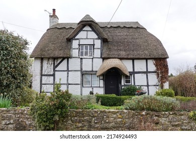 Exterior view of an old thatched cottage house on a street in an English village - Powered by Shutterstock