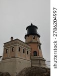Exterior view of Split Rock Lighthouse on the Lake Superior coast under a cloudy sky. Historic coastal landmark and scenic architectural landscape with natural surroundings.