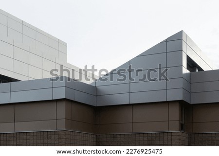 The exterior wall of a contemporary commercial style building with aluminum metal composite panels and glass windows. The futuristic building has engineered diagonal cladding steel frame panels. 