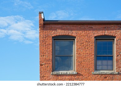 Exterior wall of red brick mill building upper story against bright blue sky in Haverhill downtown. Brick window arch, granite sill - Shutterstock ID 2212384777