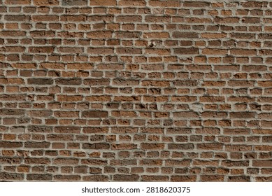 An exterior wall section of an old brick church, displaying varying shades of weathered red brick and sturdy mortar lines.